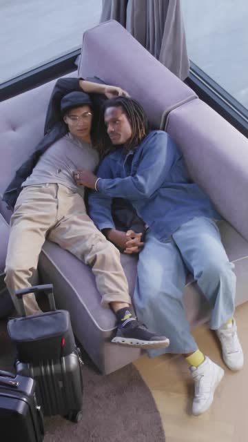 Couple Relaxing on a Couch with Suitcases Nearby.