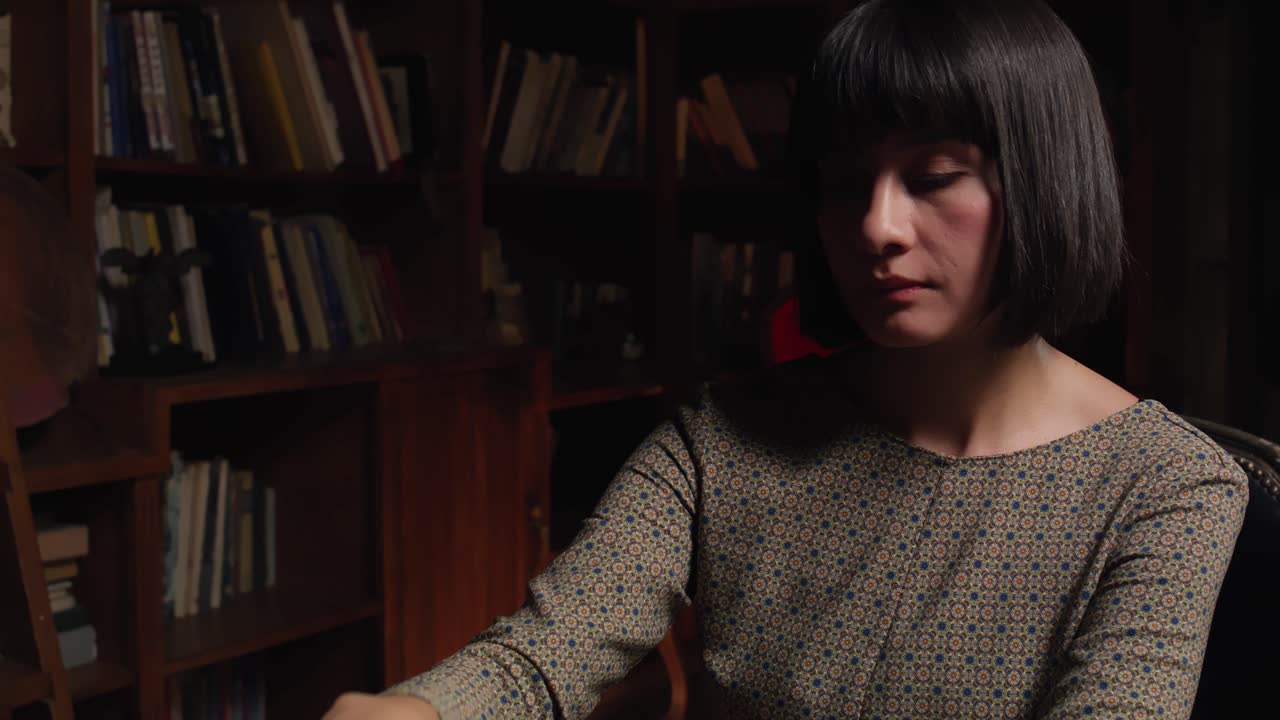 A young woman sitting in a dark room focuses on the unfolding chess ...