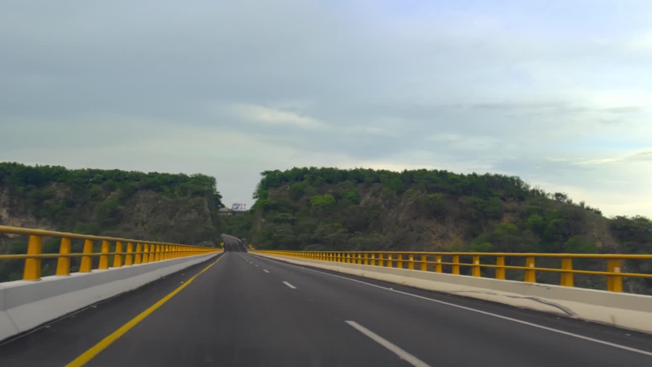 Scenic highway with yellow railings and green hills - Free Stock Video
