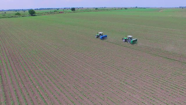 Tractors fertilizing agricultural fields.