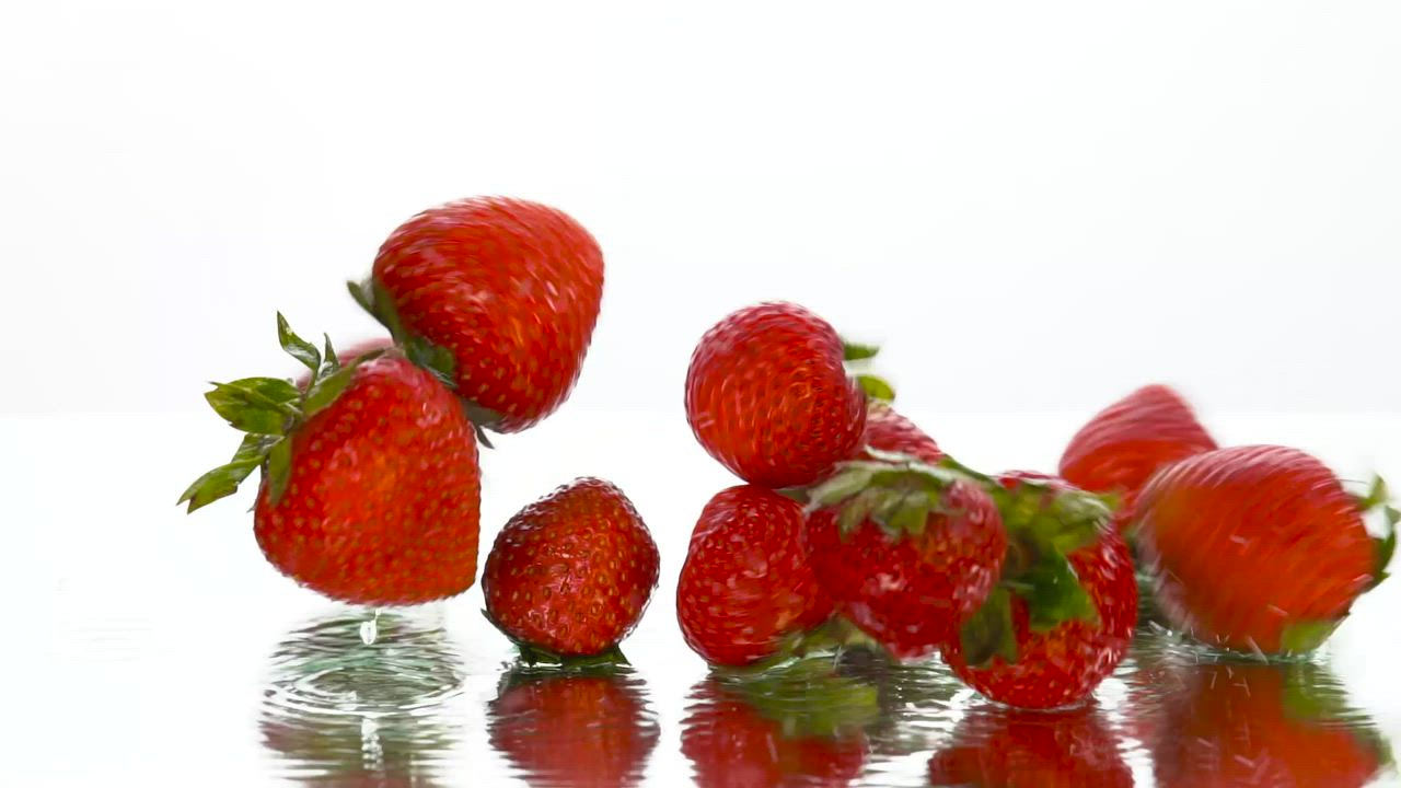 Strawberries falling on a surface on a white background - Free Stock Video->