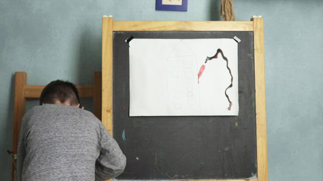Young boy painting a picture.