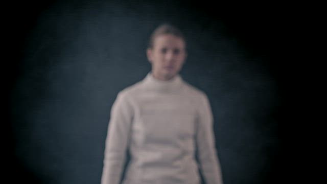 A young woman fencer posing with her sword.