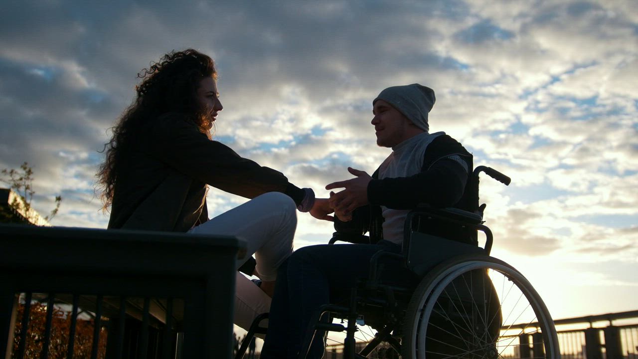Man on a wheelchair talking to a young woman in the park - Free Stock Video