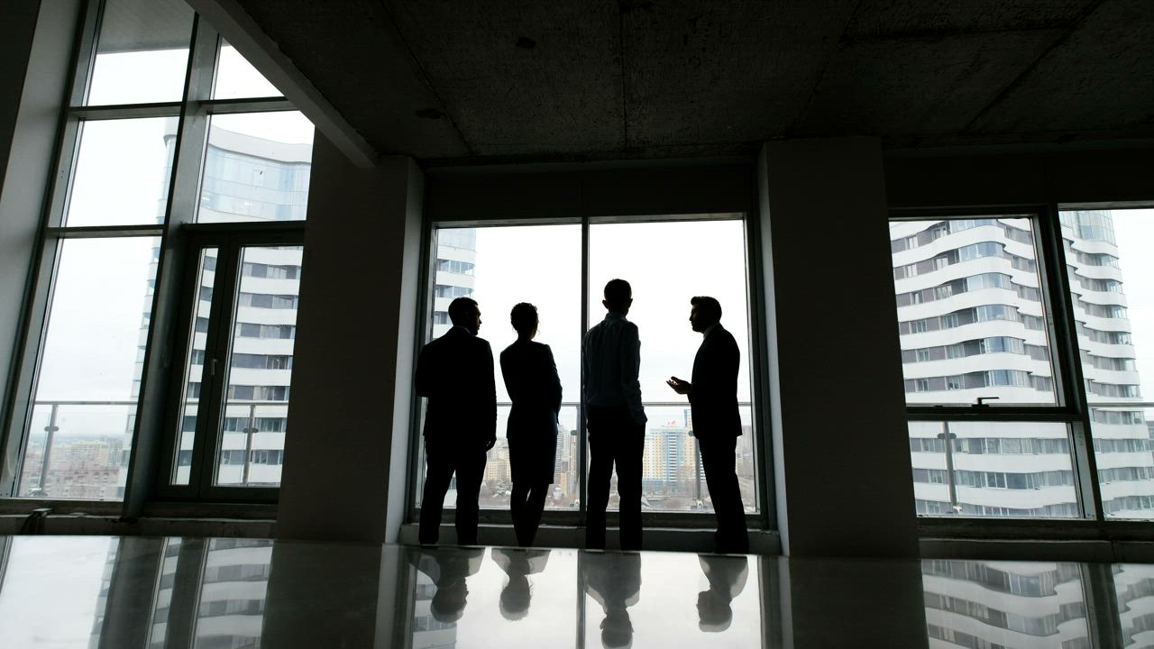 Two people in discussion beside a large office window