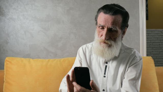 Old man taking successfully takes selfie with mobile phone.