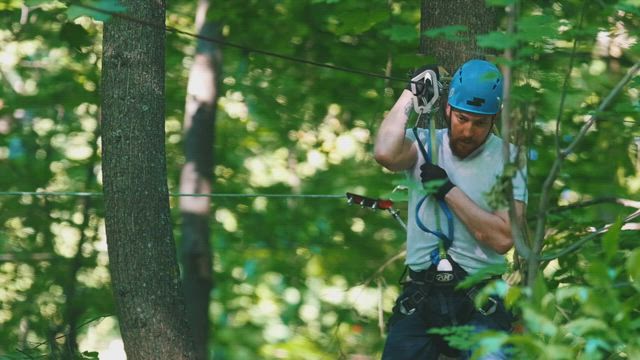 A man in a security helmet on a rope adventure in the forest .