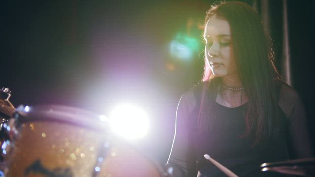 Young drummer woman performing at the stage .