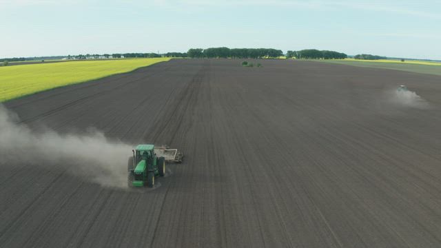 Tractor driving along a dusty field.