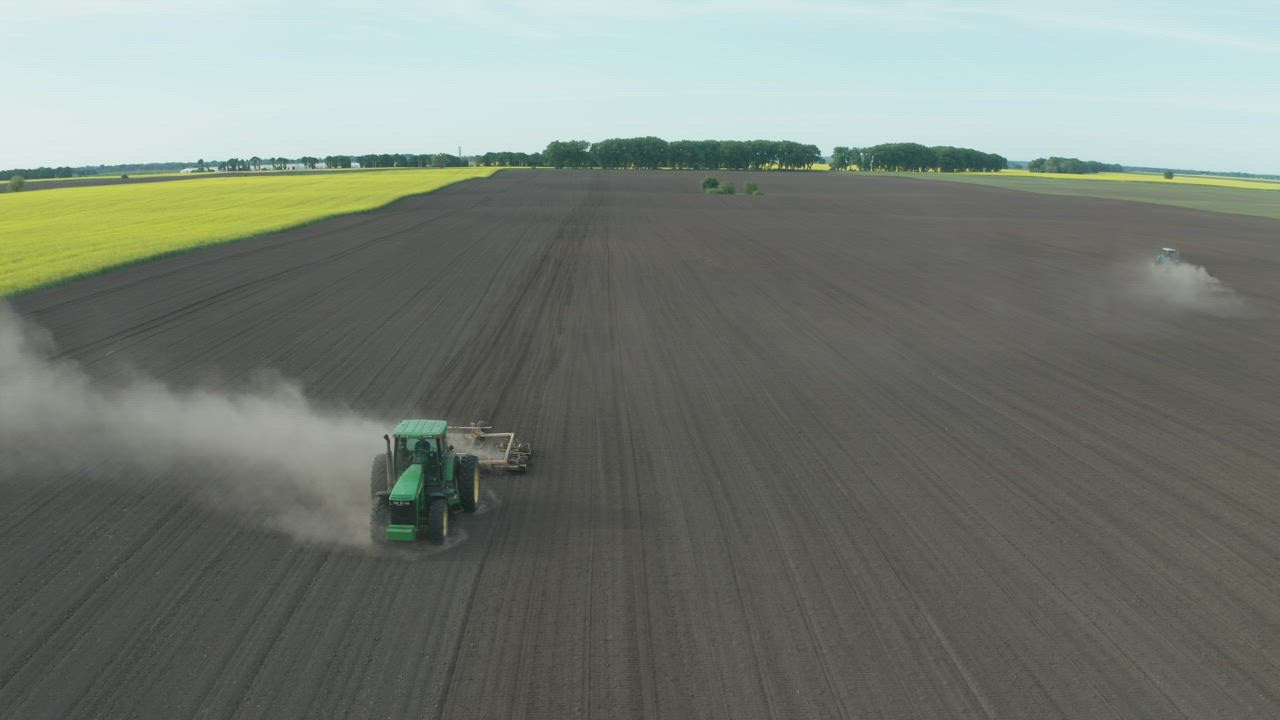 Tractor driving along a dusty field - Free Stock Video