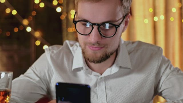 Man on mobile phone with whisky and bokeh lights.