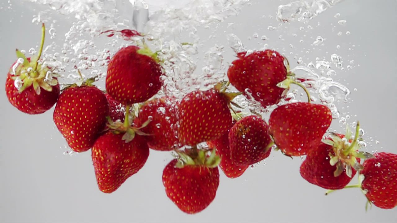 A bunch of strawberries falling through water - Free Stock Video