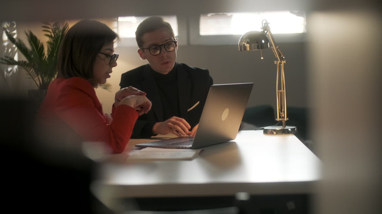 A lawyer explaining a document to a client at a laptop