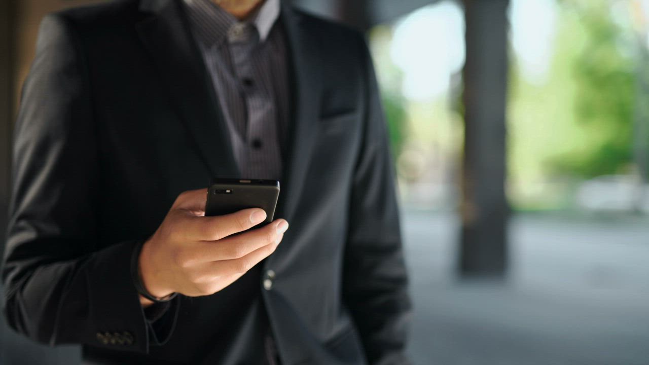 A man in a suit checking the time before making a phone call