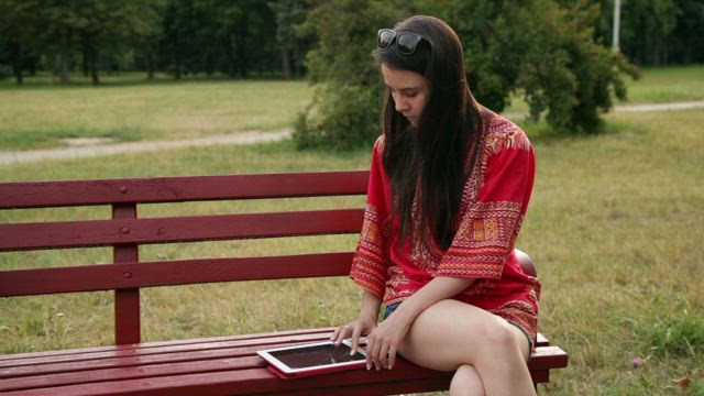 Woman using her tablet in the park.