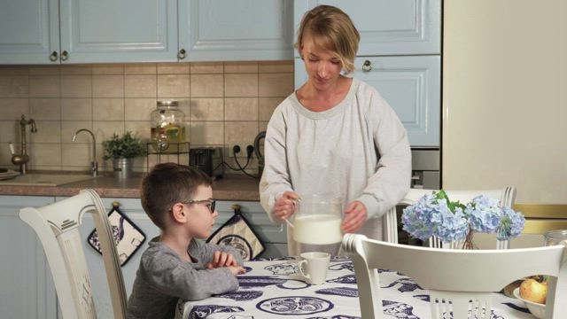 Young boy drinking milk at the table.
