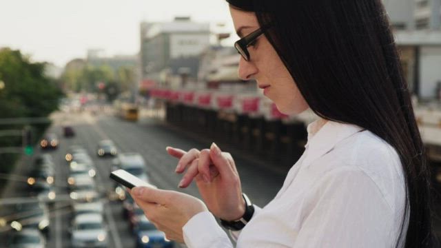 Checking her phone on a bridge.