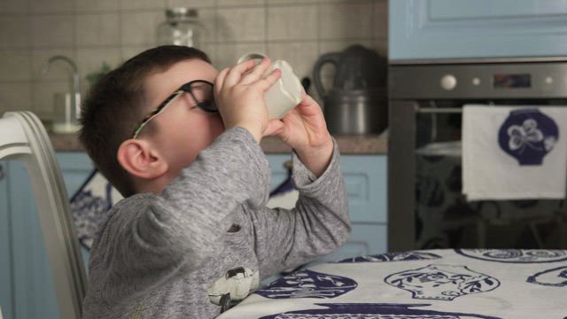 Young boy drinking from a cup.