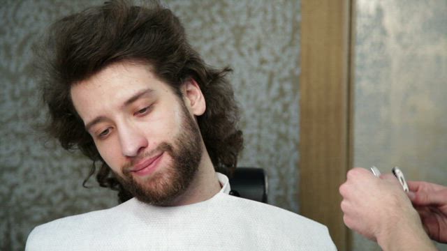 Trimming a beard with a razor, close up.