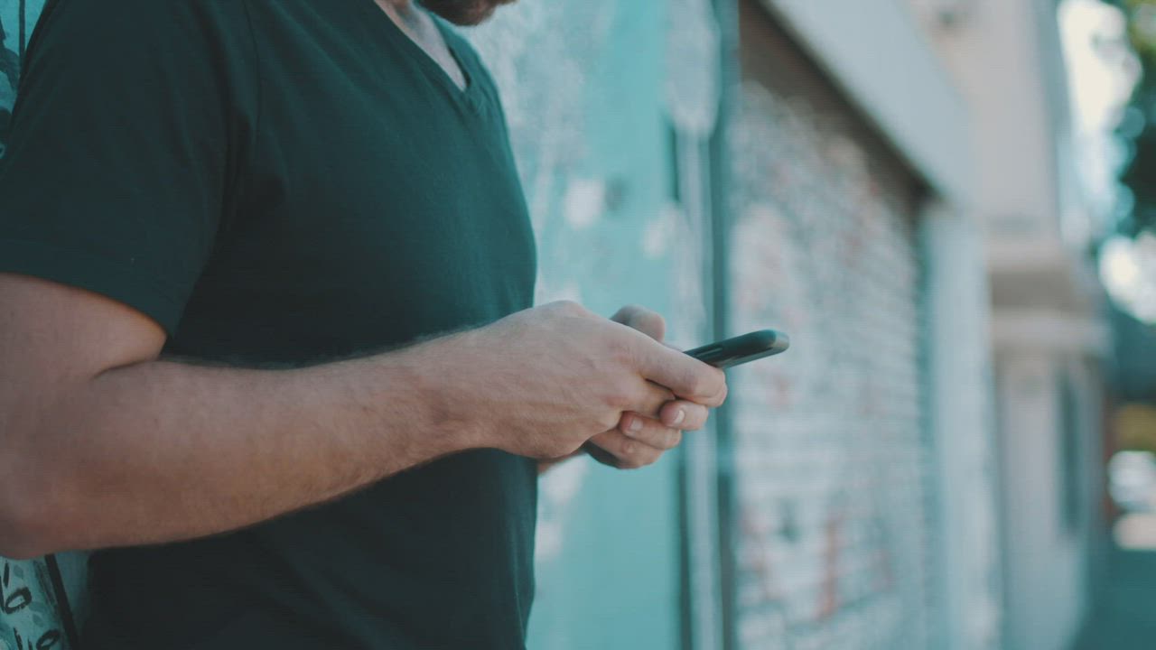 A person texting on a smartphone at the street - Free Stock Video