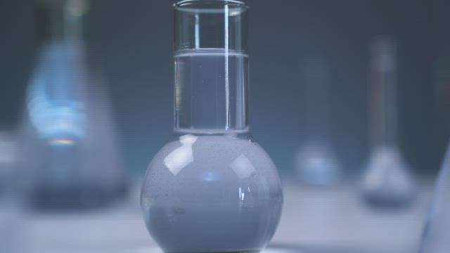 Laboratory flasks with gray liquid.