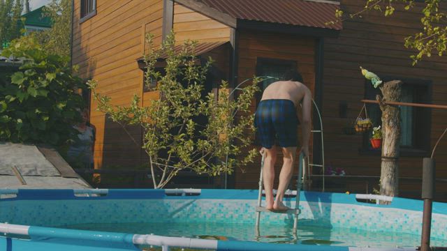 Young man jumping to an inflatable pool.