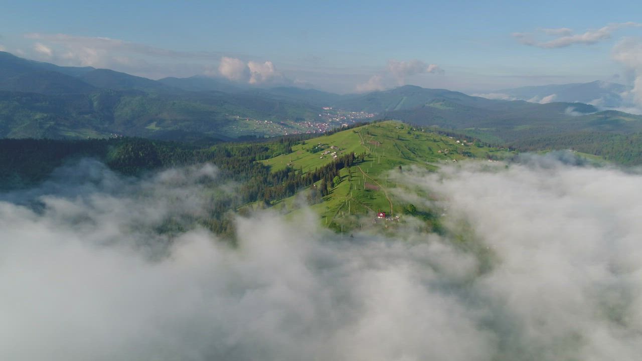 Flying above the clouds of a green valley - Free Stock Video