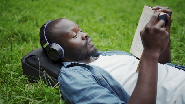 Man reading while listening to music in the park.