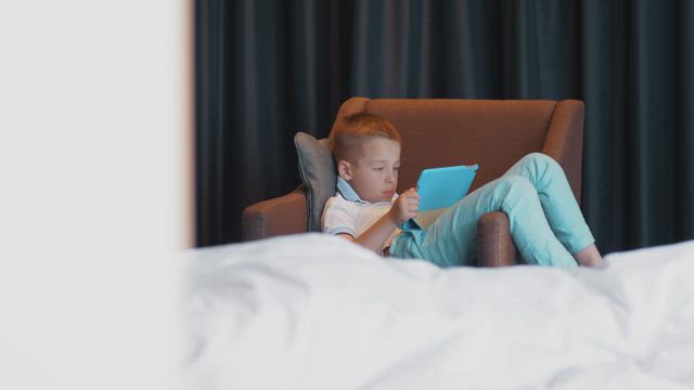 Boy watching videos on a blue tablet.