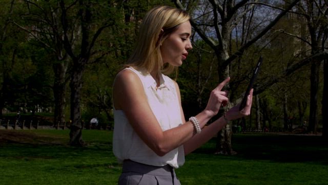 Woman taking photos in a city park.