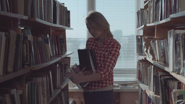 Young woman arranging the books at the library.