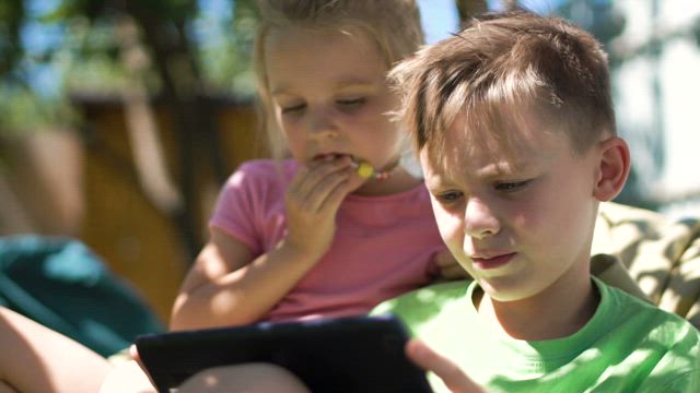 Children enjoying the tablet in the backyard.