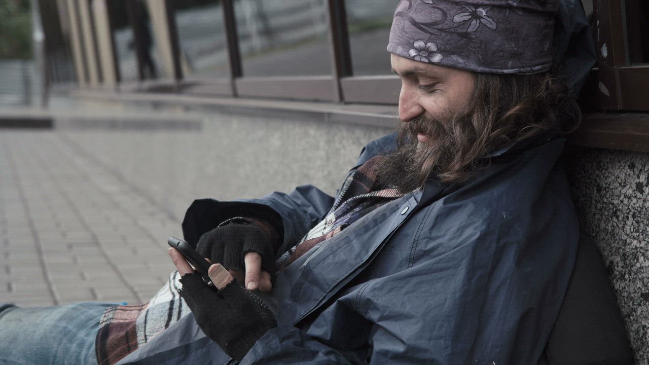 Homeless man scrolling on his phone - Free Stock Video