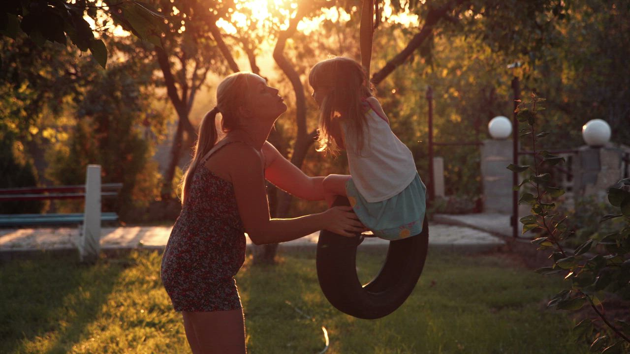 Mother kissing her daughter on the tire swing - Free Stock Video