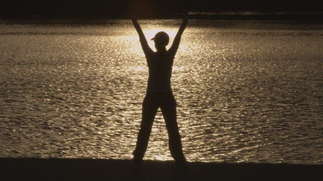 Woman stretching in the morning by a river.