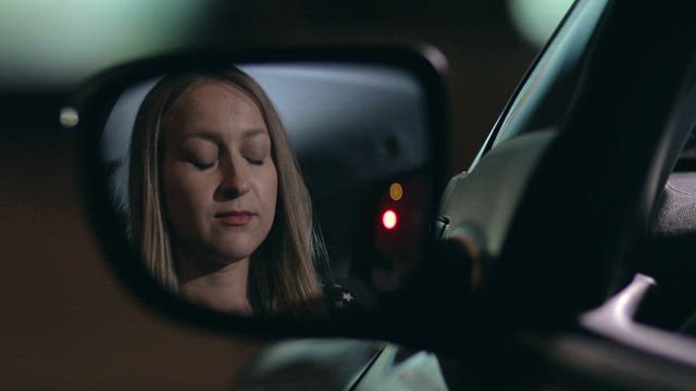 Woman applying lipstick in a car.