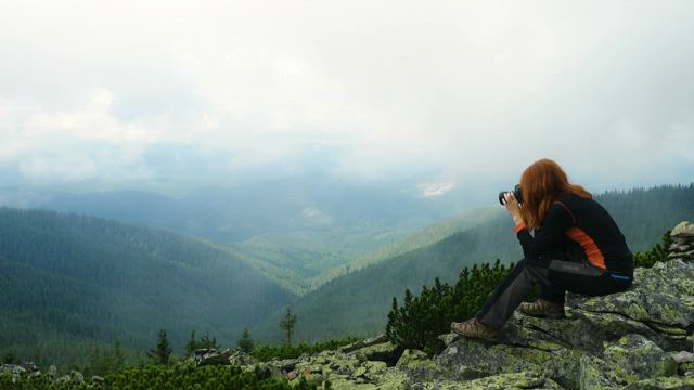 Woman taking photos in the top of the mountain.