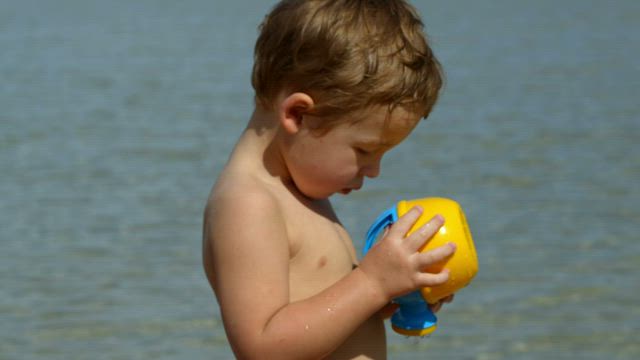 Boy looking at a beach toy.