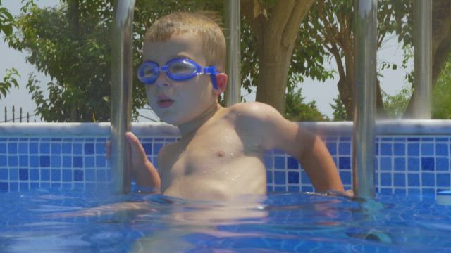 Boy climbing into a pool.