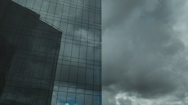 Clouds moving above a glass skyscraper.