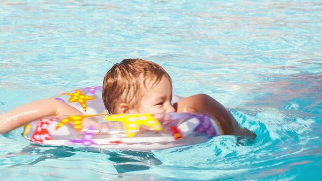 Boy swimming with a plastic ring.