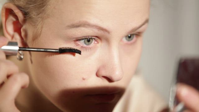 Woman applying makeup to her eyes.