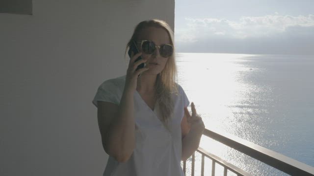 Chatting on the phone while standing on a balcony.