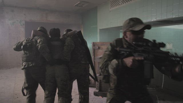 Soldiers carrying a wounded man through a building.
