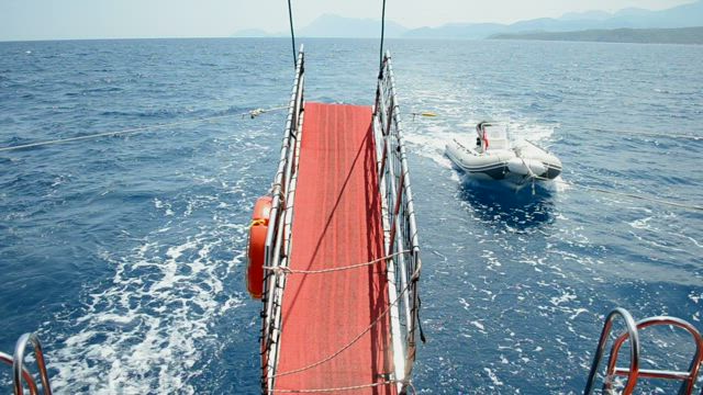 Small boat behind a large yacht.