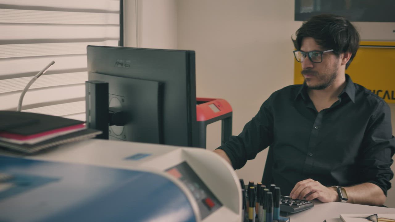 Working on the computer in a studio with printers - Free Stock Video