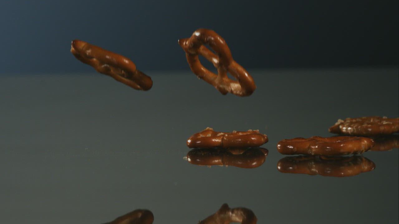 Pretzels falling into a mirror surface - Free Stock Video