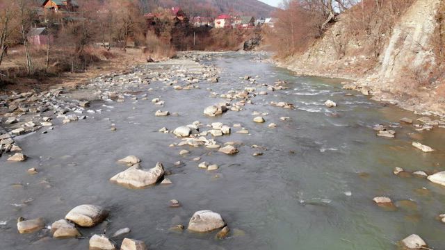 Plane over a mountain river with rocks.