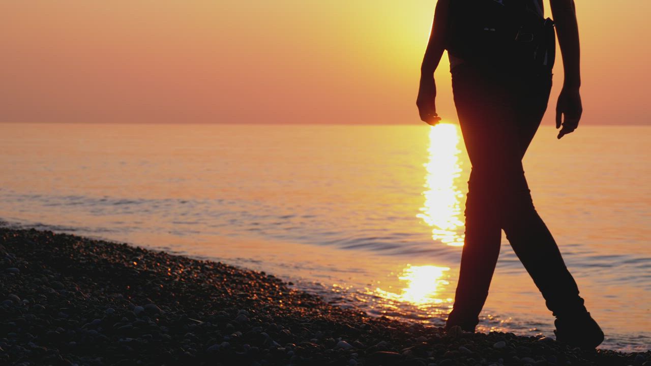 Silhouette of woman walking on the beach at sunset - Free Stock Video