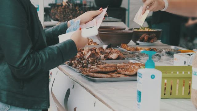 Customer buying grilled meat at the market.